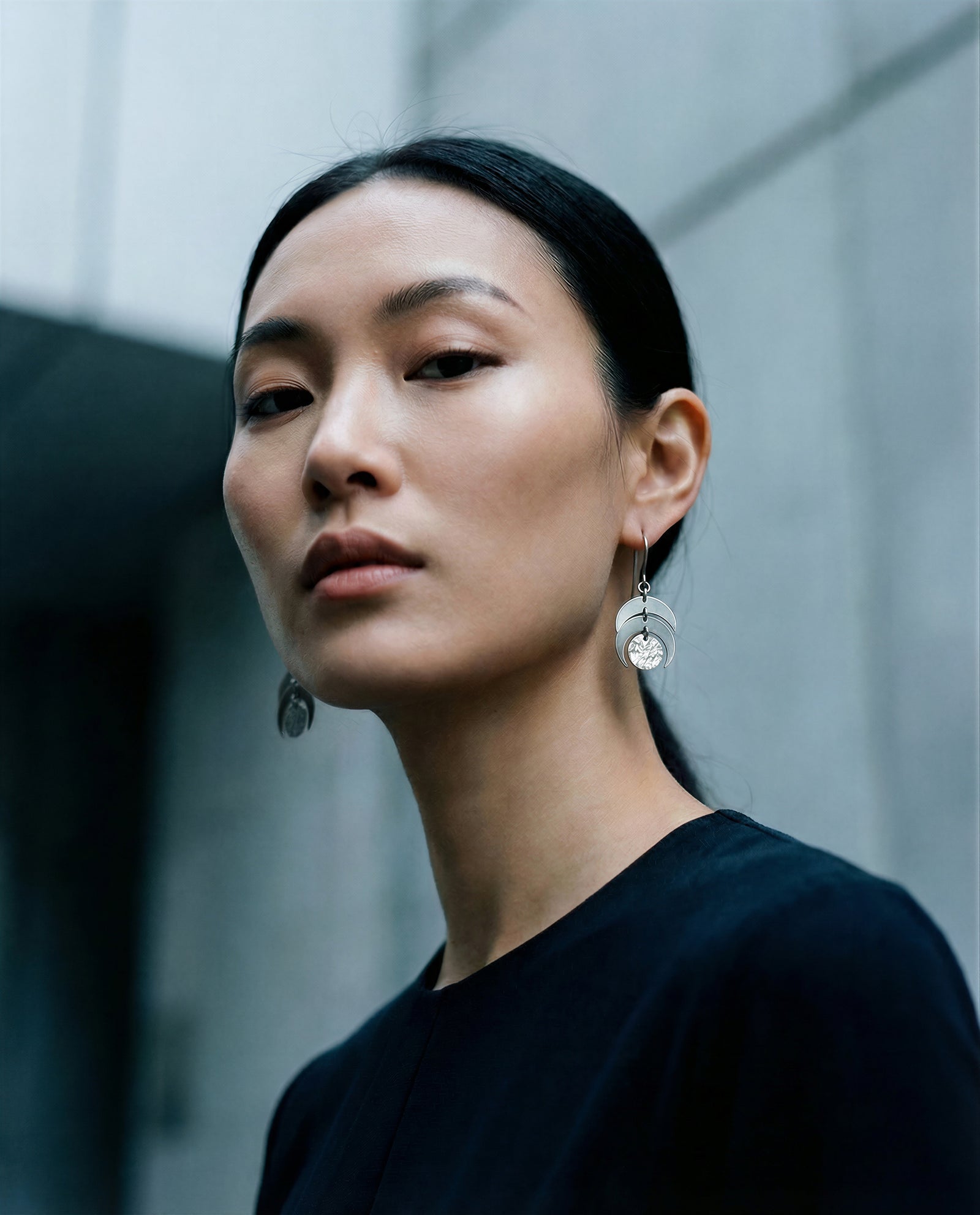 Woman wearing the Luna Moon Phase Earrings in 20mm width and the all silver colour way from Lawless Jewellery