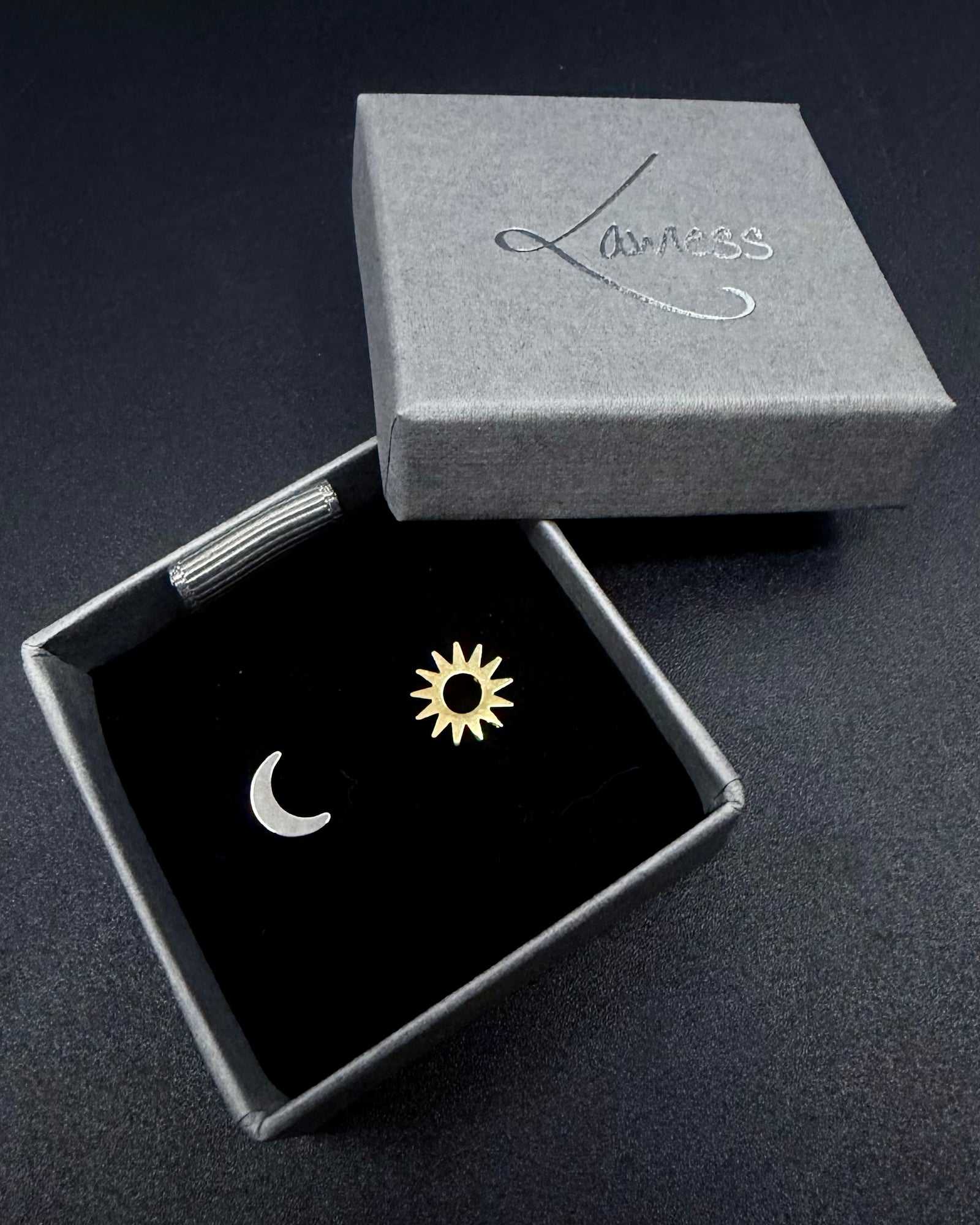 Mismatched pair of Eos Equinox stud earrings featuring a small silver crescent moon and a gold sun.