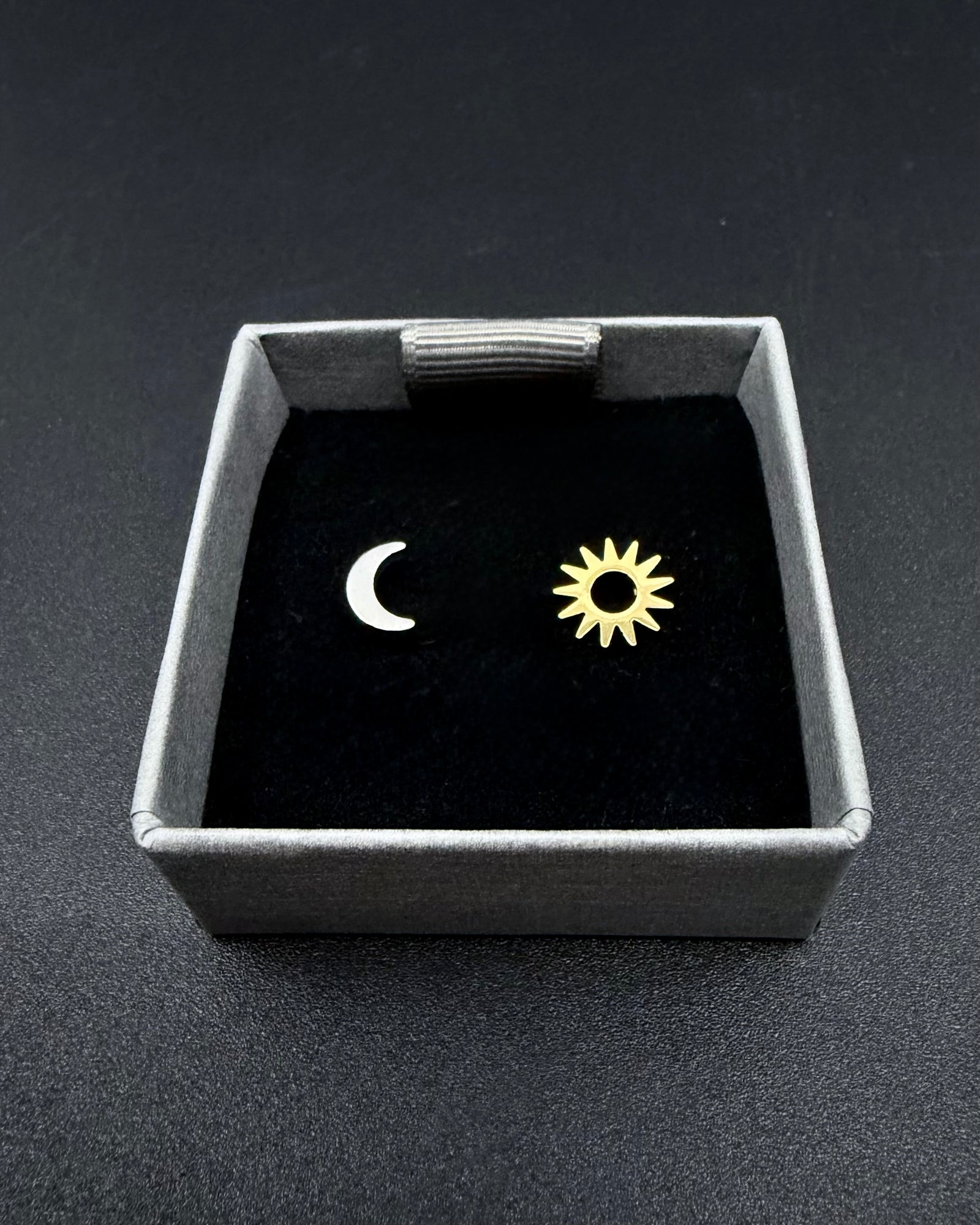 Mismatched pair of Eos Equinox stud earrings featuring a small silver crescent moon and a gold sun.