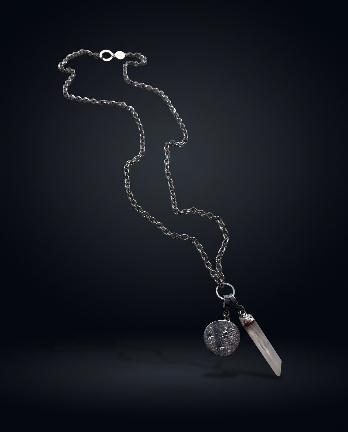 Long Length Hecate silver charm necklace suspended against a dark background, with an 80cm textured chain, clear quartz point and round Star Gazer Disc.