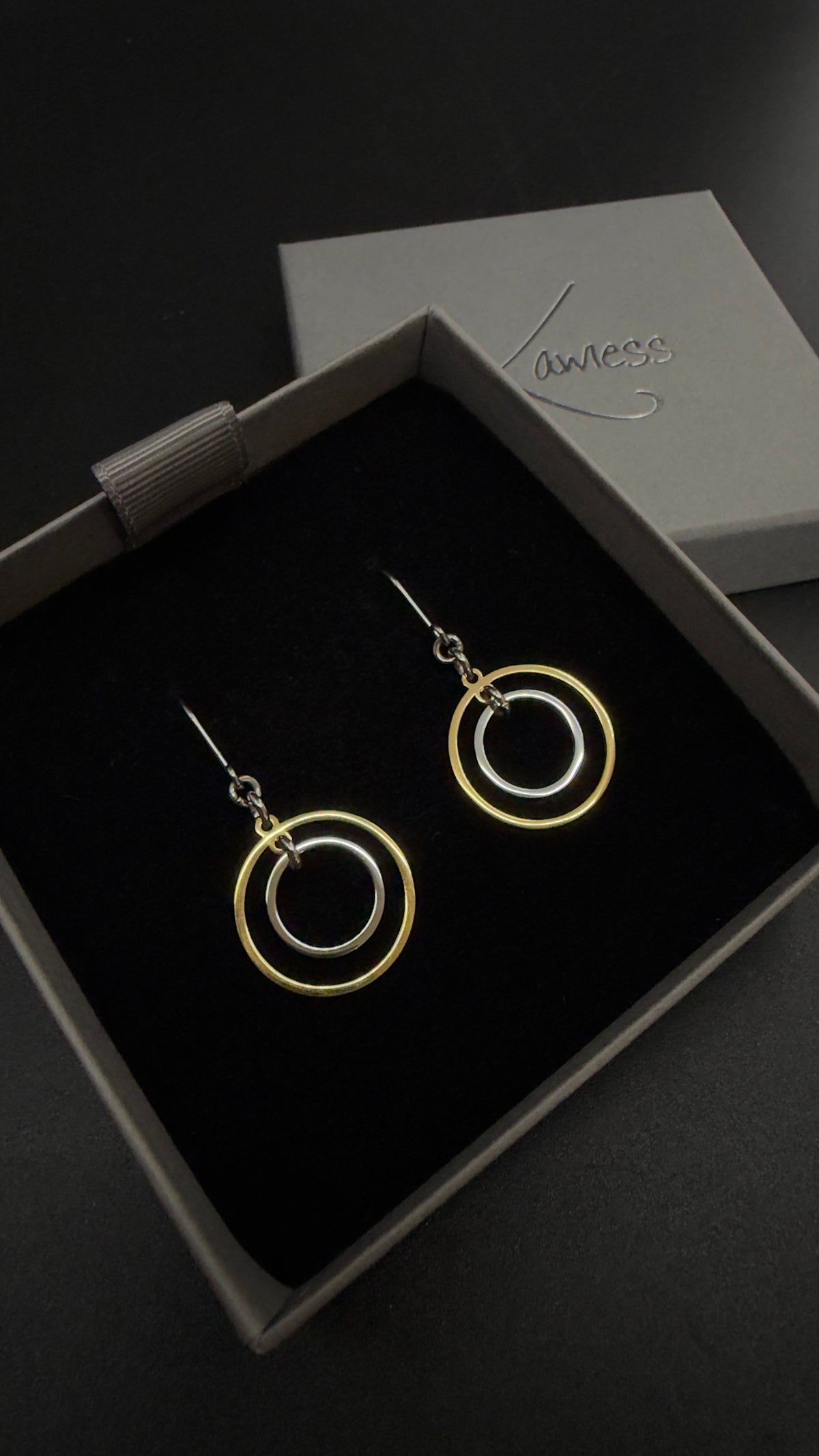 Pair of Cassini Align drop earrings with gold outer rings, silver inner rings and silver hooks displayed in a grey Lawless jewellery box.