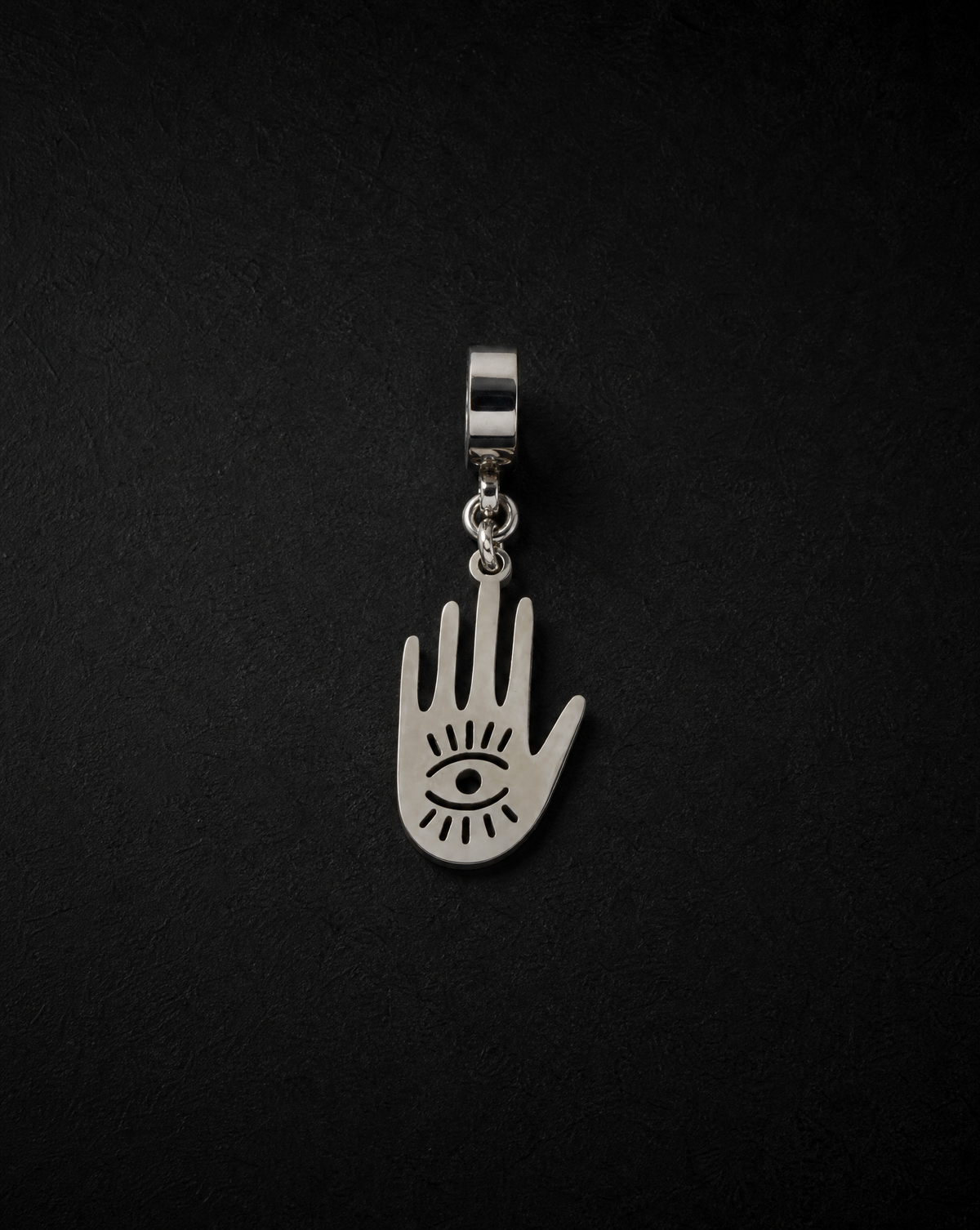 Silver Hecate Protector Charm shaped as an open hand with a watchful eye and radiating cut-out details, displayed against a black background.