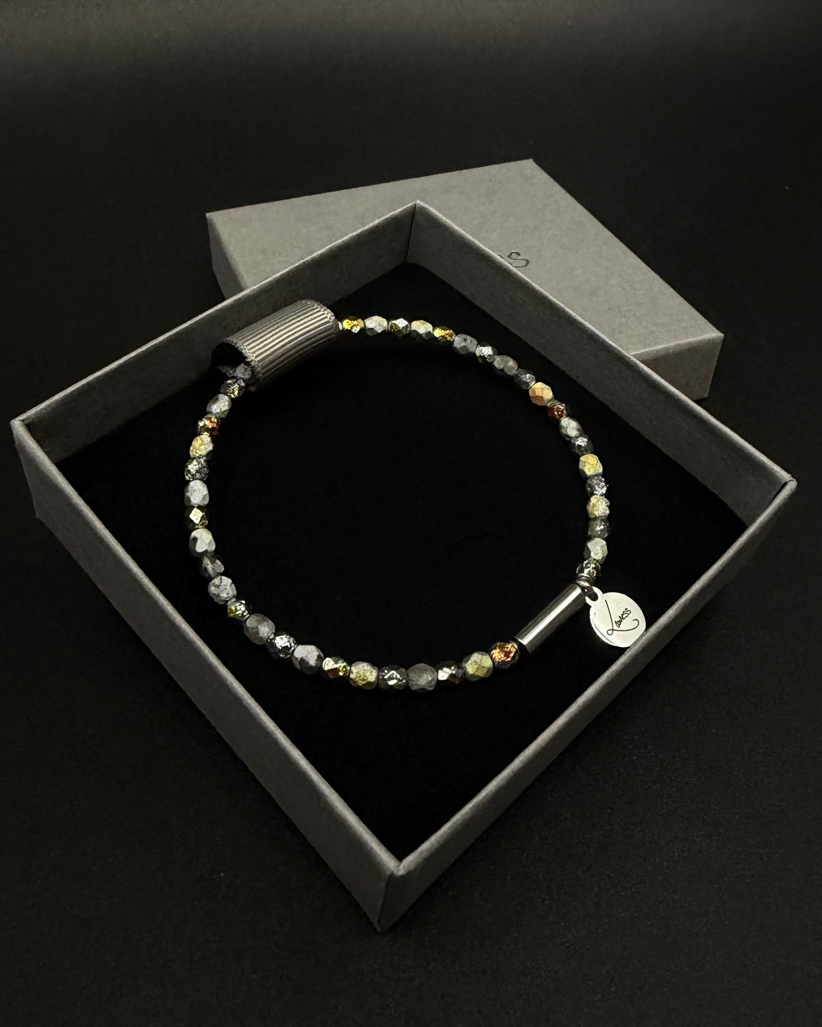 Eos Flare Bracelet made from dark faceted fire-polished crystal beads with mixed metallic flashes, a silver screw clasp and Lawless logo tag.