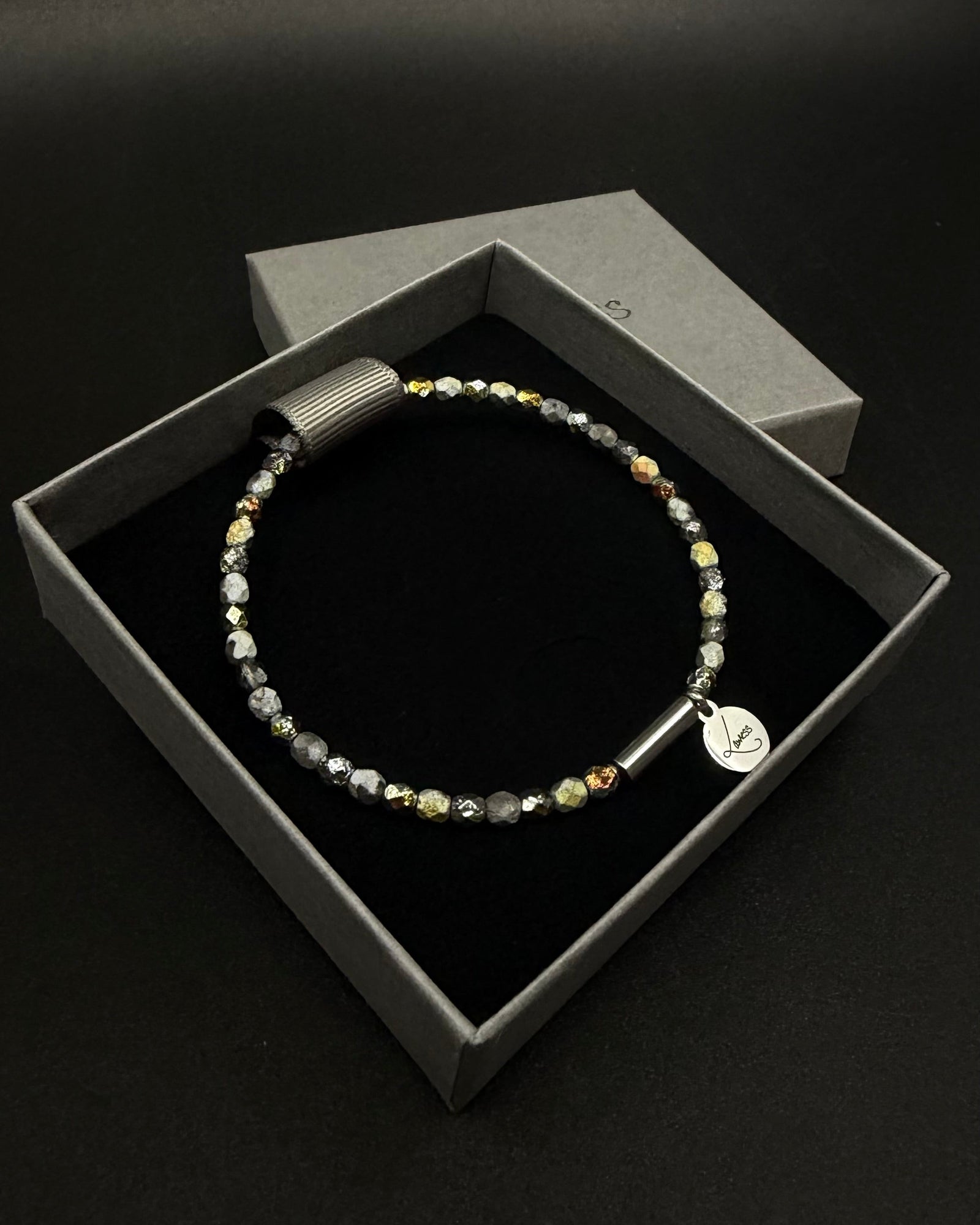 Eos Flare Bracelet made from dark faceted fire-polished crystal beads with mixed metallic flashes, a silver screw clasp and Lawless logo tag.