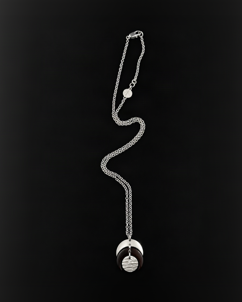 Silver and black Luna Phase Necklace featuring layered crescent shapes and a textured silver lunar disc on a silver chain against a black background.