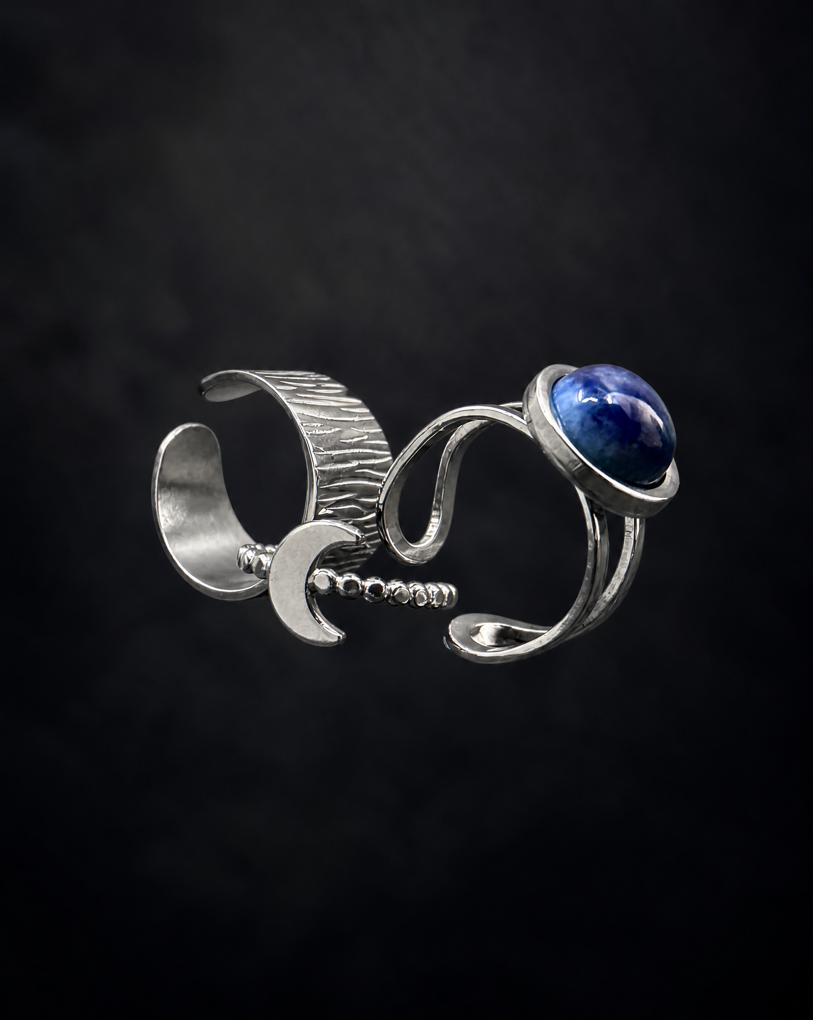 Three adjustable silver Nebulae rings featuring a domed blue lapis lazuli cabochon, a wide linear-textured band and a crescent moon design.
