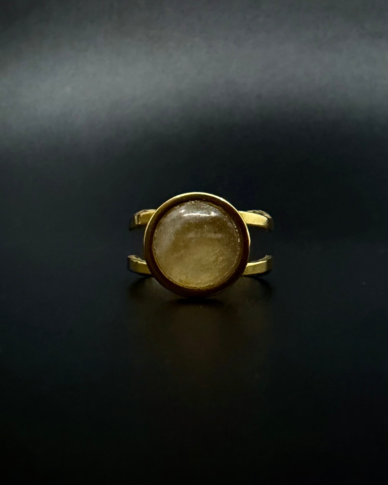 Gold ring with a circular stone on a dark background