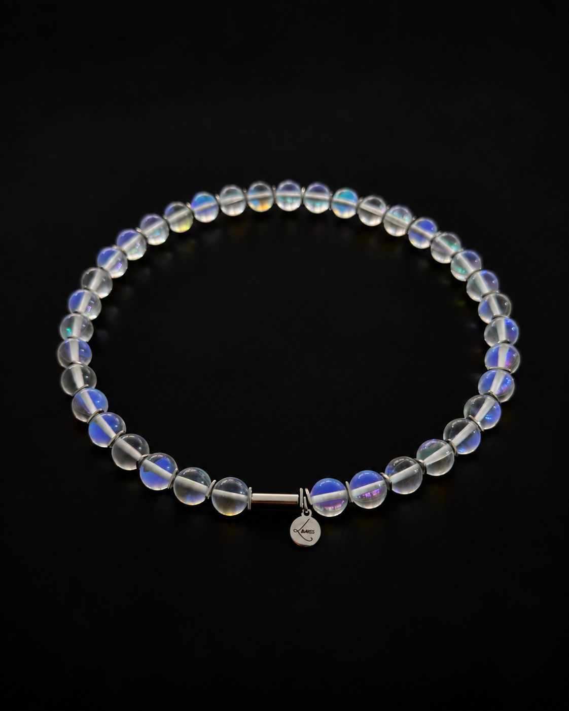 Nebulae Field Necklace featuring a strand of 10mm transparent iridescent glass beads with blue, violet and gold reflections, silver spacers, a stainless steel screw clasp and Lawless logo tag against a black background.