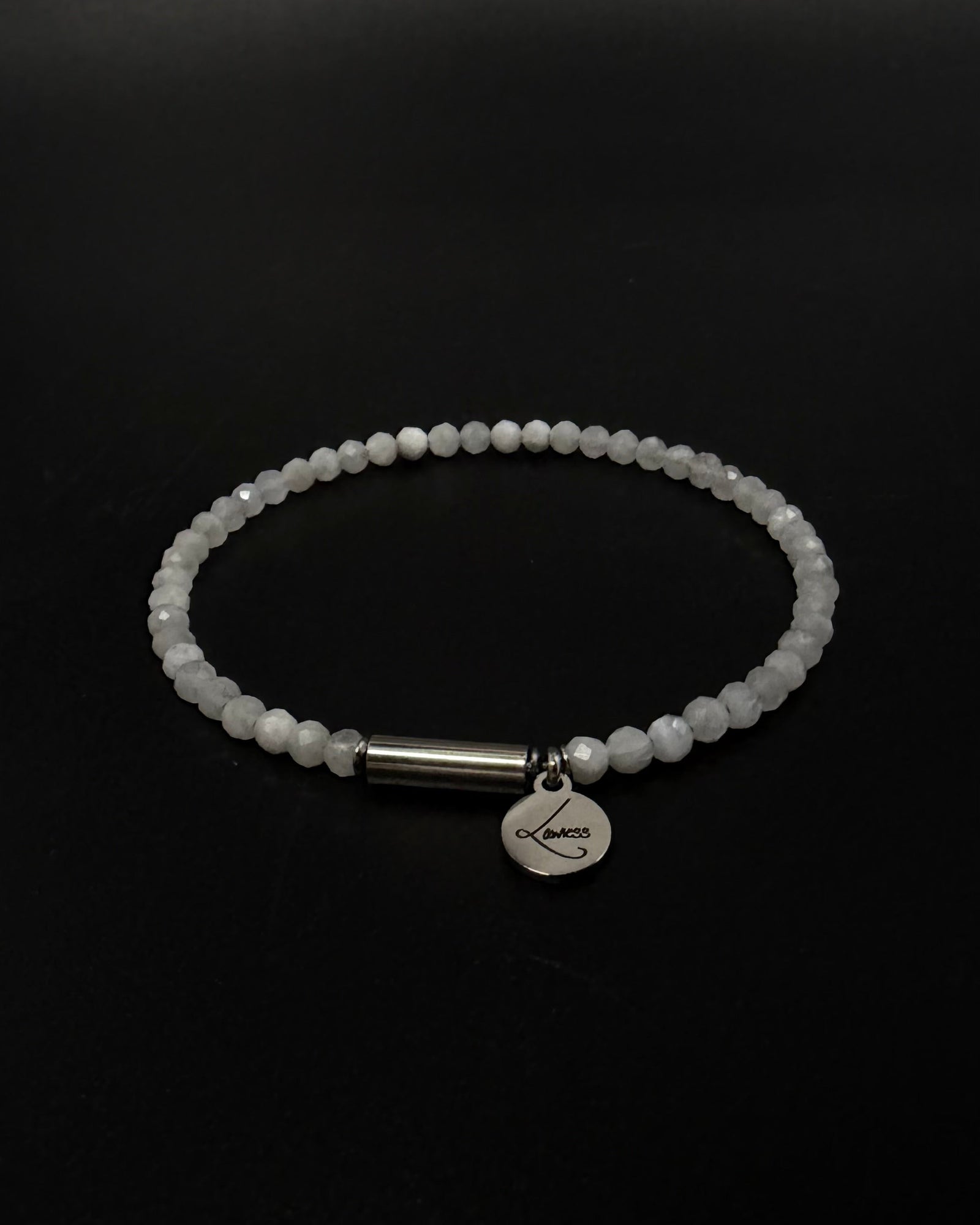 Selene Anew Bracelet made from faceted white moonstone beads with a silver cylindrical screw clasp and round Lawless logo tag against a black background.