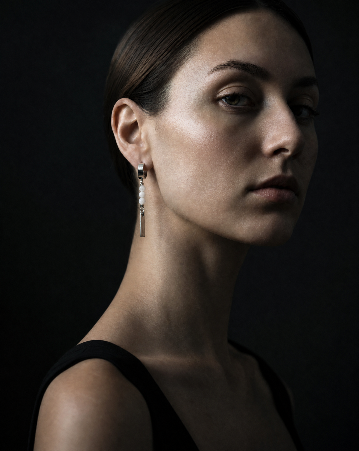 Woman wearing earrings against a dark background