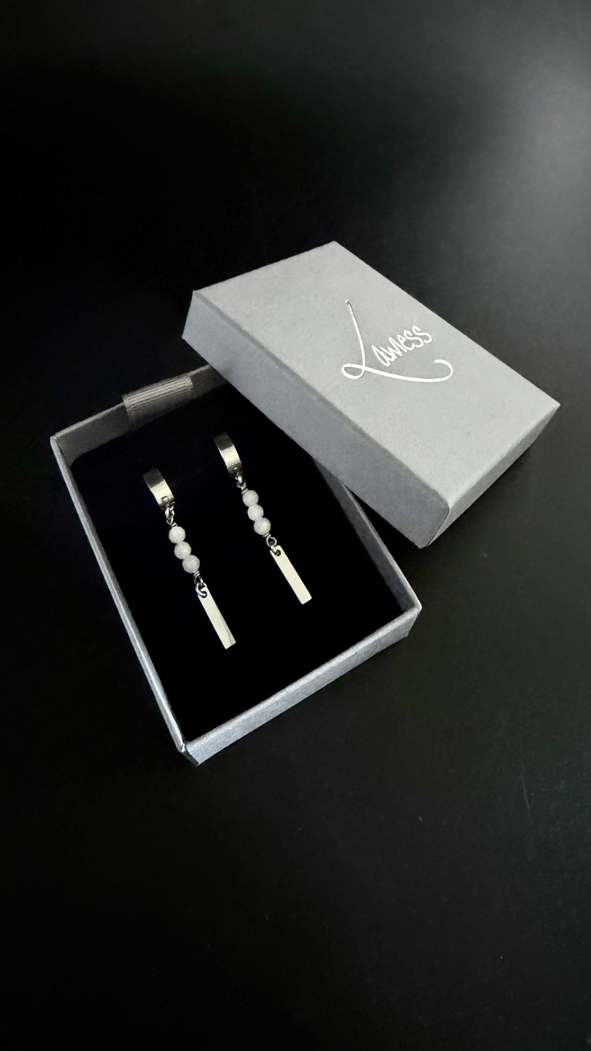 Jewelry displayed in a box with Lawless branding on a dark background