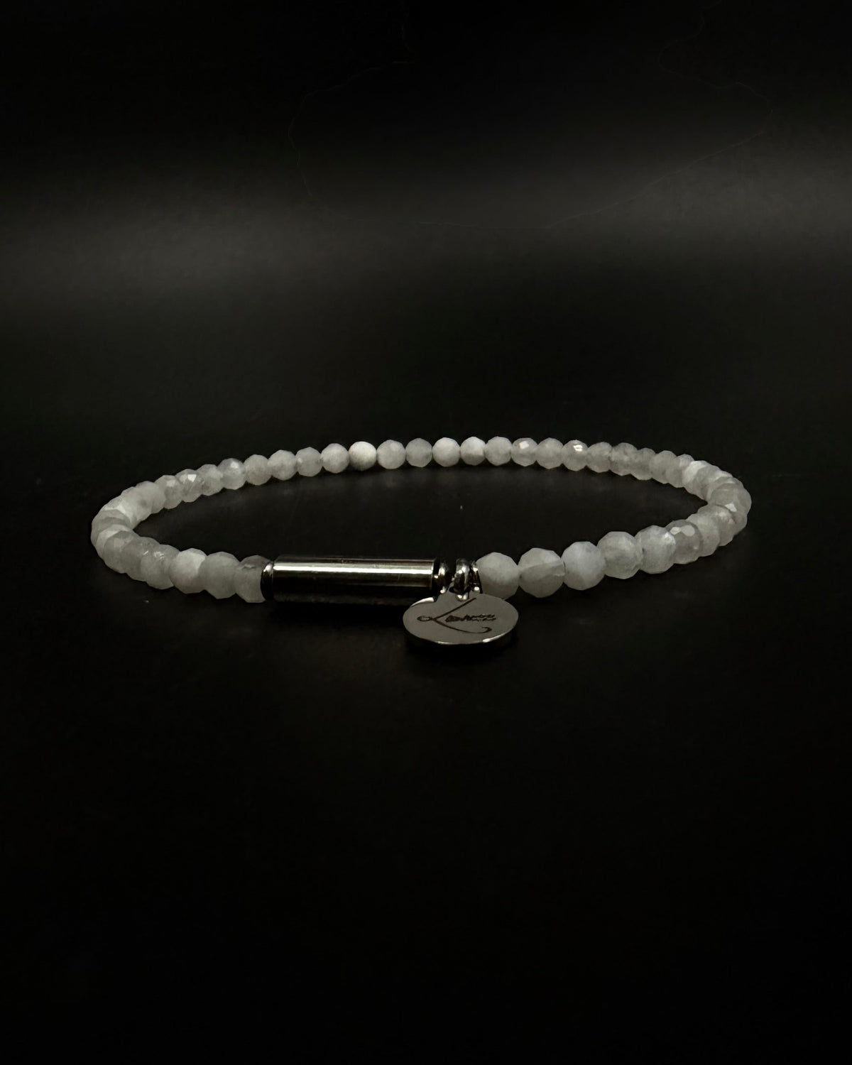 Selene Anew Bracelet made from faceted white moonstone beads with a silver cylindrical screw clasp and round Lawless logo tag against a black background.
