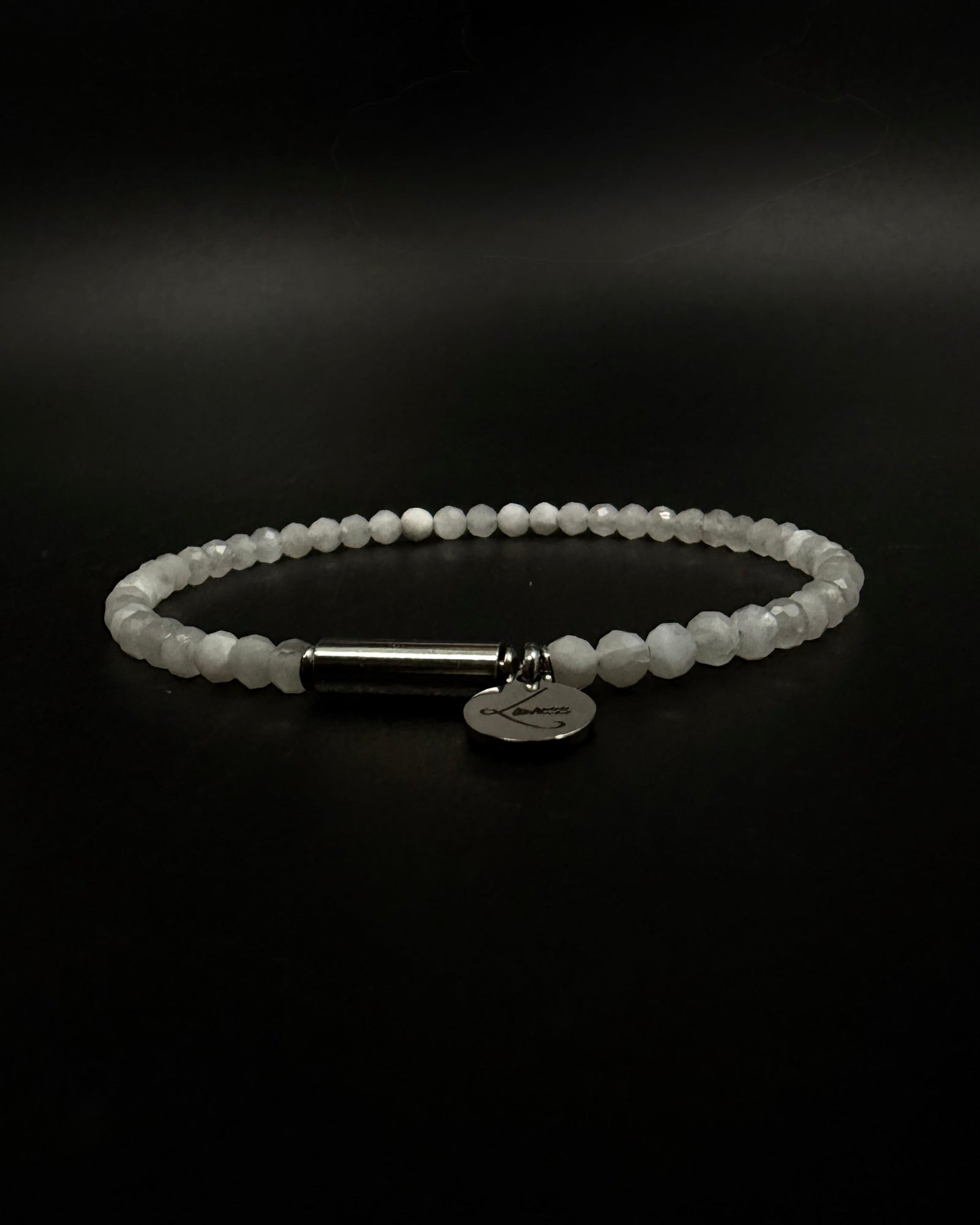 Selene Anew Bracelet made from faceted white moonstone beads with a silver cylindrical screw clasp and round Lawless logo tag against a black background.