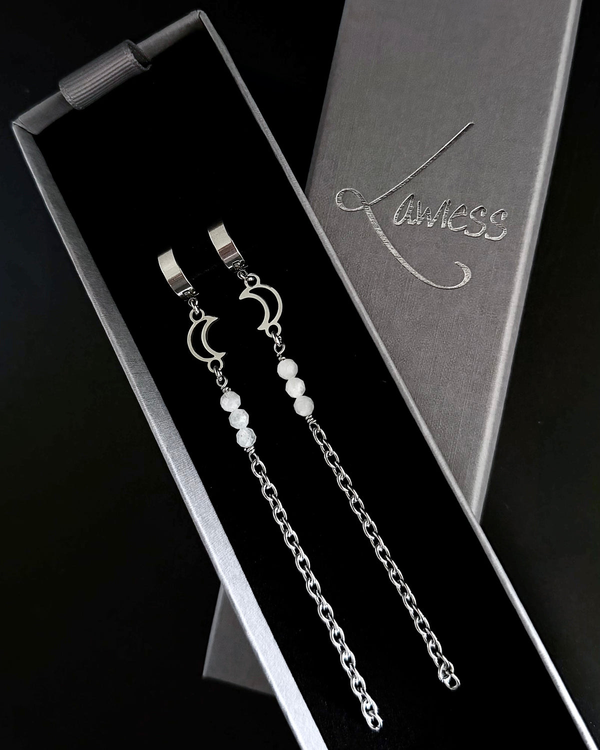 Silver earrings with beads in a branded box on a black background