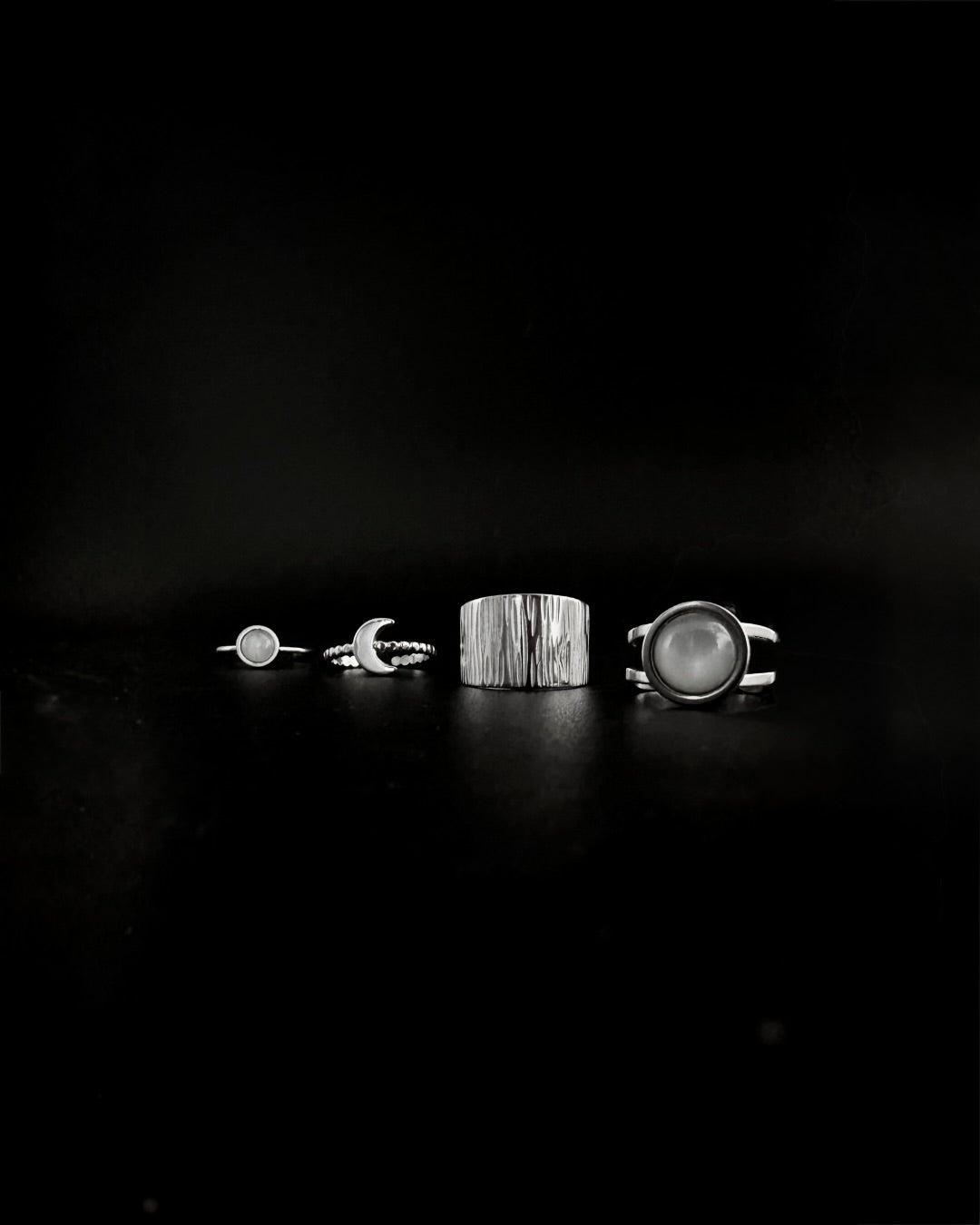 Four rings displayed on a dark surface with a black background