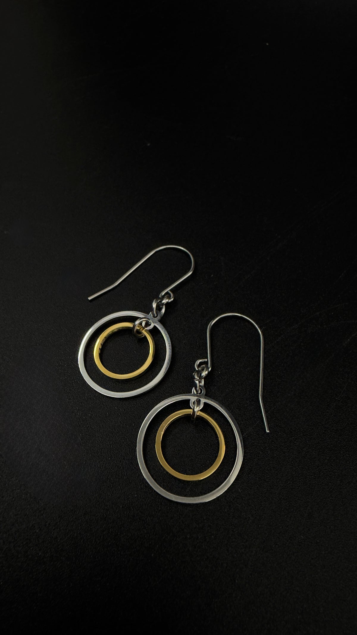 Pair of Cassini Align drop earrings with silver outer rings, gold inner rings and silver stainless steel hooks.