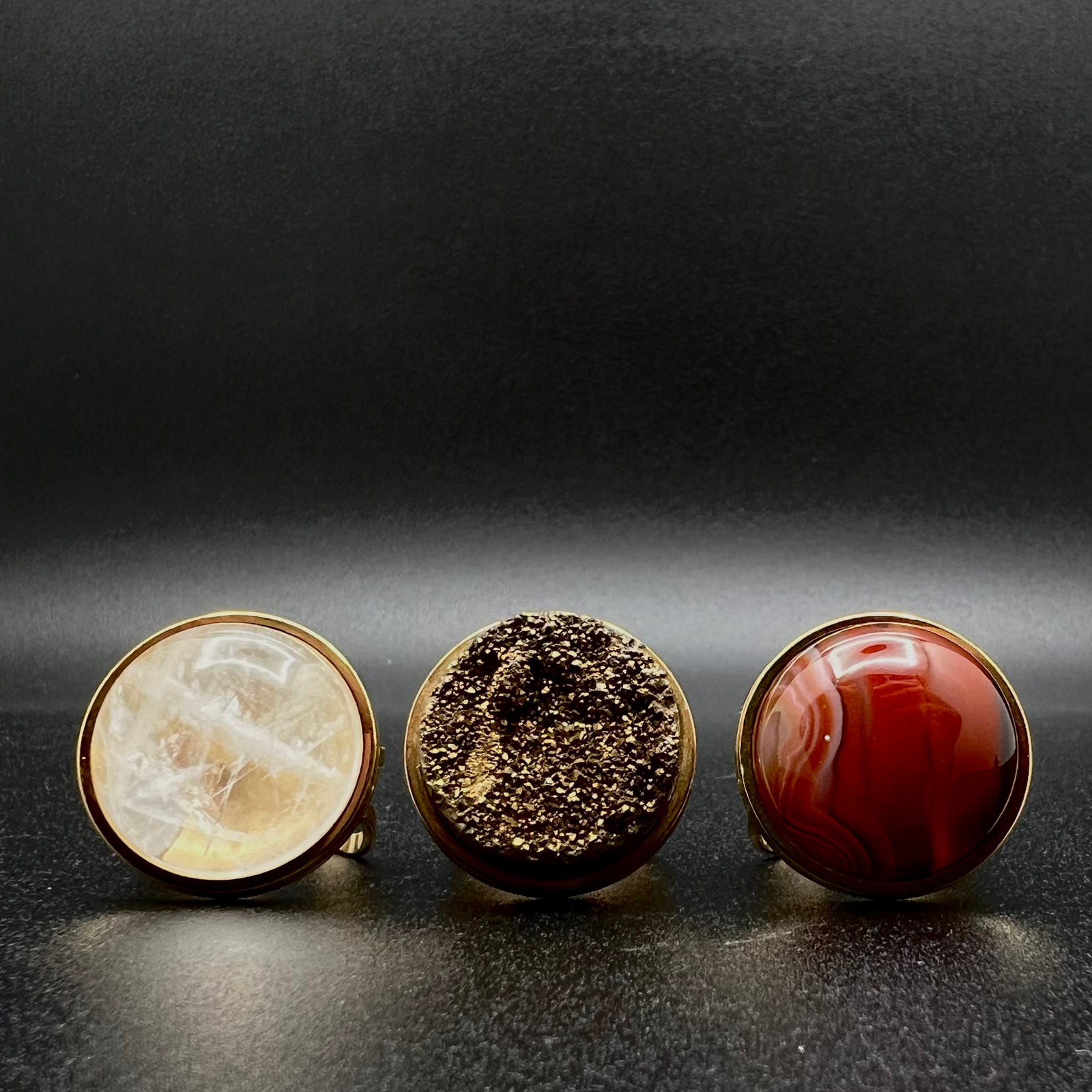 Set of three gold-plated stainless steel rings featuring 20 mm cabochons in Clear Quartz, Gold Druzy, and Carnelian on adjustable double-shank bands — Lawless Jewellery.