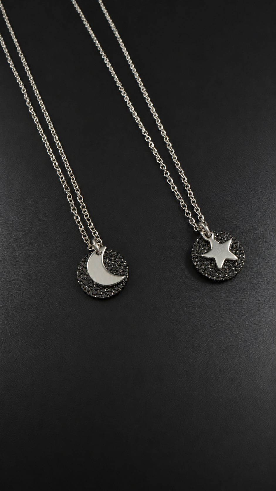Urania Cipher Necklace with a silver chain and textured black reversible pendant featuring a silver crescent moon on one side and a star on the other.